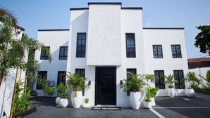 A modern building with a black door and multiple windows, surrounded by potted plants. - The Hendon House (Lagos)