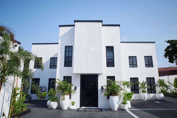 Un bâtiment moderne avec une porte noire et de nombreuses fenêtres, entouré de plantes en pot.