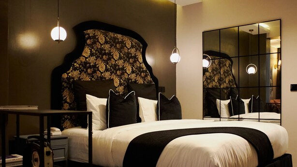 A modern bedroom with a large bed, bedside tables, a mirror, and a ceiling light fixture. - The Hendon House (Lagos)