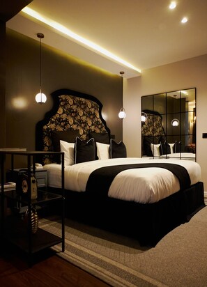 Une chambre moderne avec un grand lit, des tables de chevet, un miroir et un luminaire au plafond.