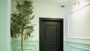 A hallway with a black and white checkered floor, a dark door, and a potted plant. - The Hendon House (Lagos)