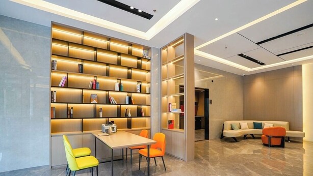 A modern library with a central table and chairs, surrounded by bookshelves. - yi xuan hotel - bus station (Yangjiang)