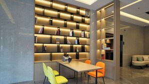 A modern library with a long table and chairs, surrounded by bookshelves with illuminated shelves. - yi xuan hotel - bus station (Yangjiang)