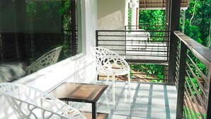 An outdoor balcony with white chairs and a table, surrounded by glass railings and a thatched roof. - Eco Vista (Somvarpet)