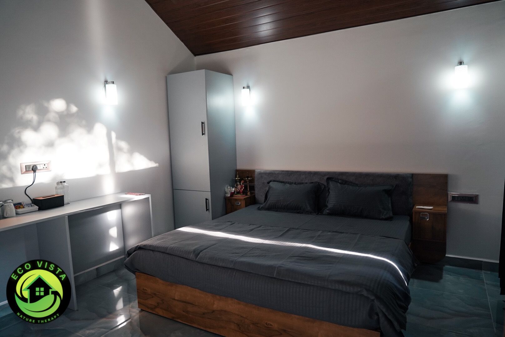 Un dormitorio moderno con una cama grande, mesitas de noche, un armario y un escritorio con una lámpara.