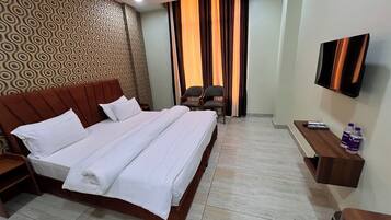 Una habitación de hotel con una cama grande, un televisor en la pared y un escritorio con una silla.