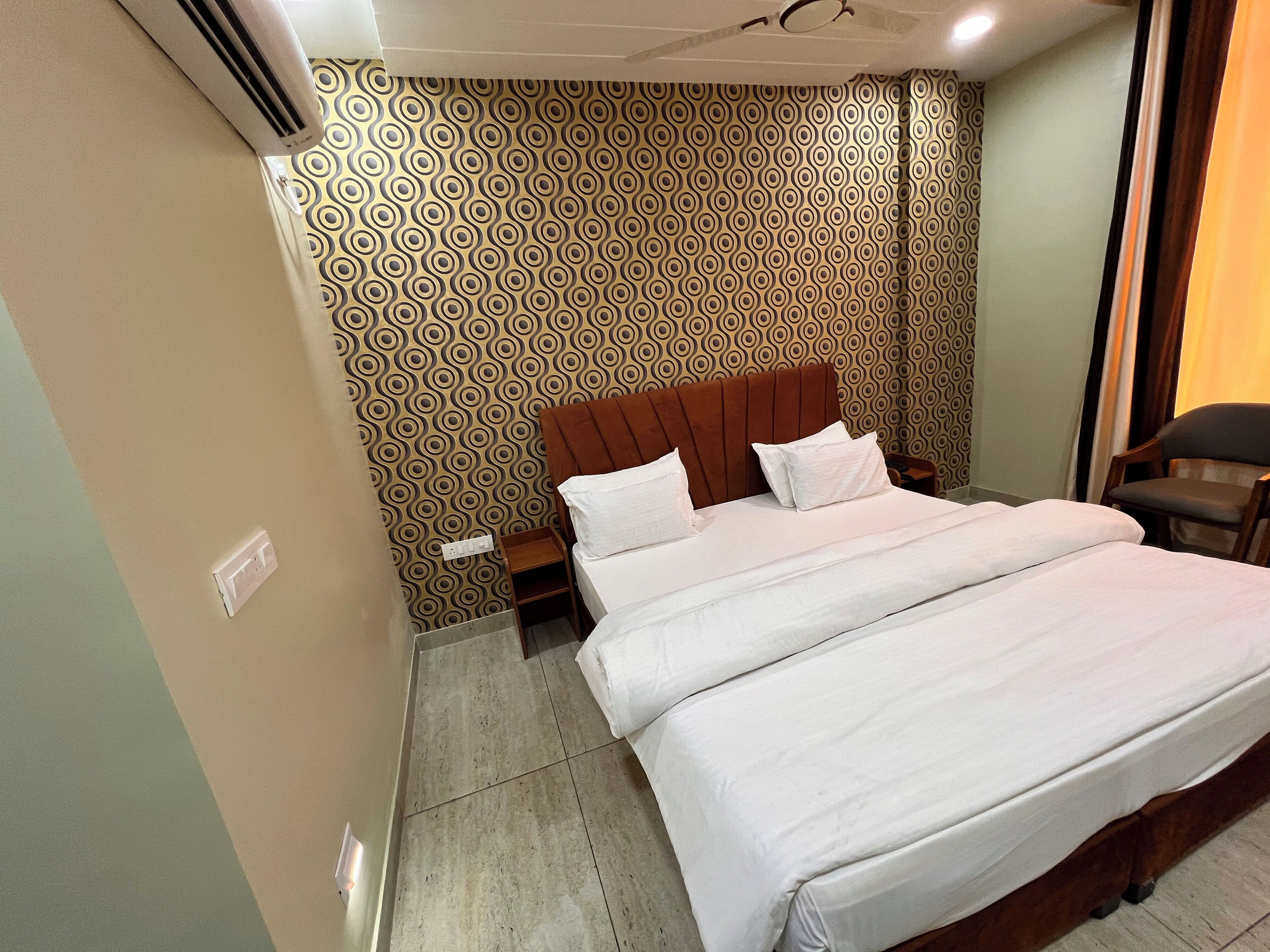 A hotel room with a bed, a nightstand, and a chair.