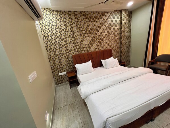 A hotel room with a bed, a nightstand, and a chair. - Hotel Kesari (Sujangarh)