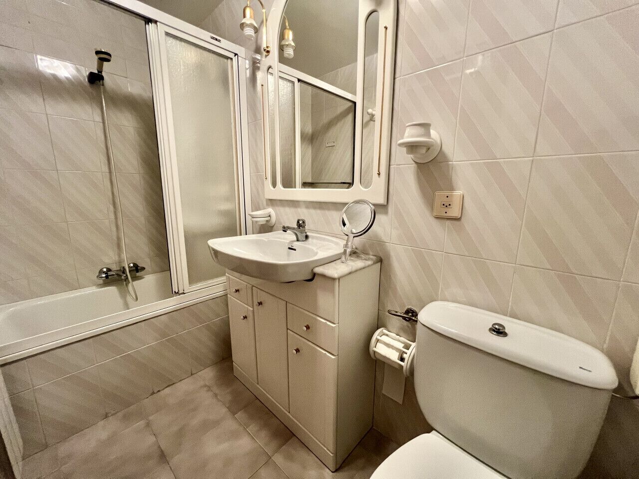 Un baño con bañera, lavamanos, inodoro y espejo.