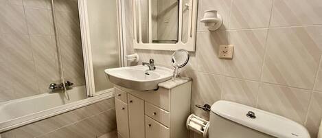 Un baño con bañera, lavamanos, inodoro y espejo.