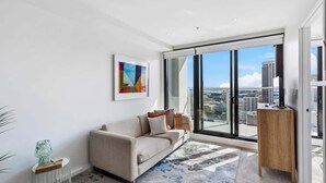 A modern living room with a sofa, a coffee table, and a large window with a city view.