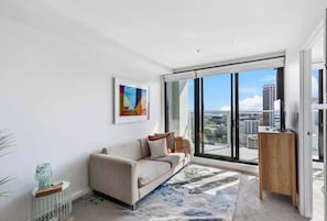 Uma sala de estar moderna com um sofá, uma mesa de centro e uma janela grande com vista para a cidade.
