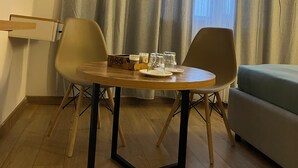 A small dining area with a round table, two chairs, and a box of condiments. - Tikhii Zamok (Bishkek)
