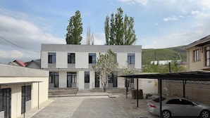A modern building with a flat roof, large windows, and a paved courtyard. - Tikhii Zamok (Bishkek)