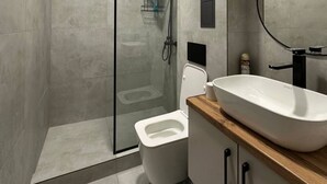 A modern bathroom with a glass-enclosed shower, a white toilet, and a wooden vanity with a large sink. - Tikhii Zamok (Bishkek)