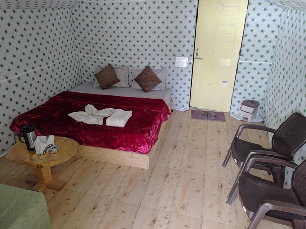 A room with a bed, two chairs, a small table, and a door. - Anupam River Side Camps And Cottage (Kasol)