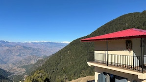 Ein Gebäude mit rotem Dach und Balkon, umgeben von einer gebirgigen Landschaft.