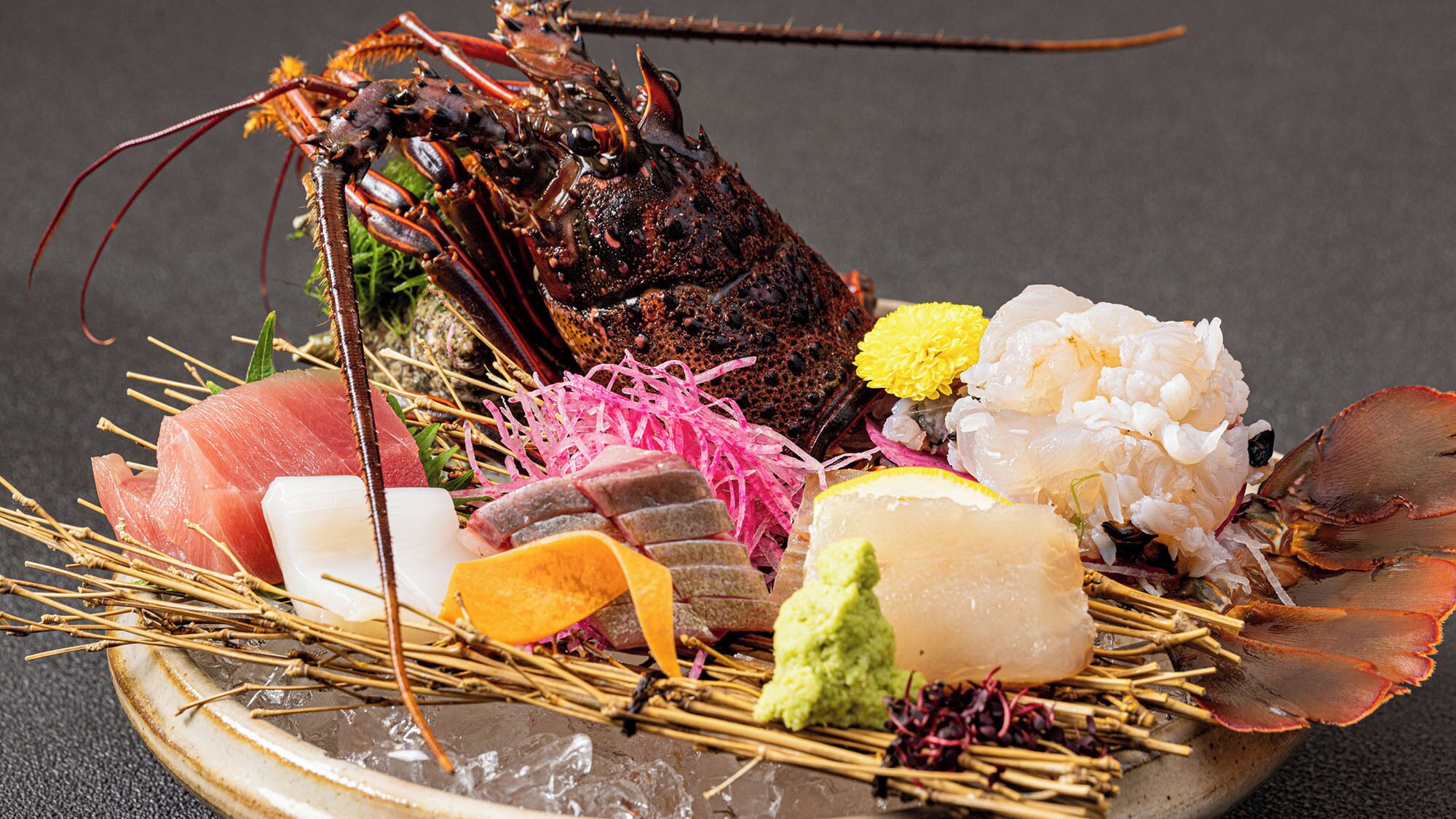A seafood platter with various items including a lobster, sashimi, and other seafood delicacies.