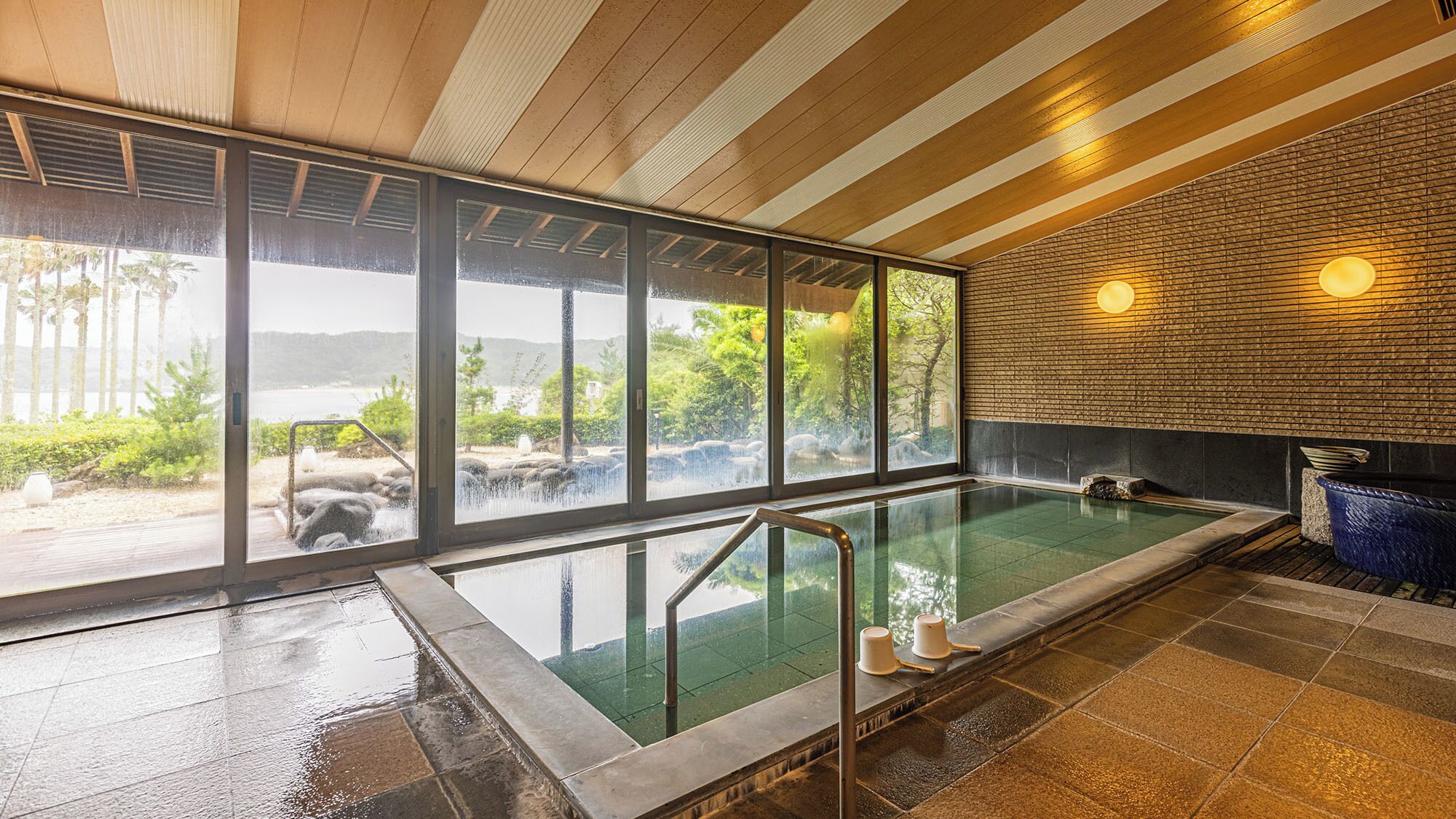 A modern indoor pool with large windows, a brick wall, and a view of a natural landscape.