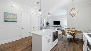 A modern kitchen with white cabinetry, a central island, and pendant lighting.