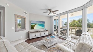 A spacious living room with a large TV, comfortable seating, and a balcony with a view. - St Lucia 306*Guest Favorite*HighEnd*ResortAmenites (Destin)