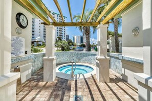 Un espace piscine doté d’un jacuzzi circulaire, d’une pergola en bois et de palmiers.