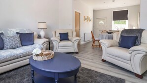 A living room with a sofa, armchairs, a coffee table, and a dining area with a table and chairs. - Canal View (Skipton)