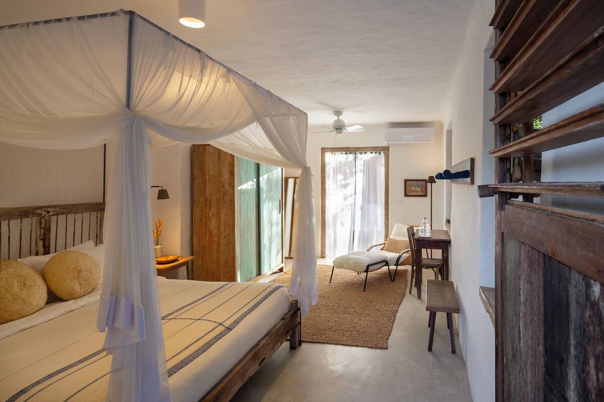 Una camera da letto con un letto a baldacchino, una scrivania con una sedia e vista sull'esterno.