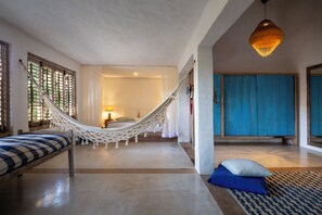 A room with a hammock, a bed, a blue cabinet, and a hanging light fixture. - Vila Santo Rei (Porto Seguro)