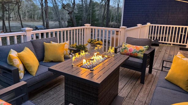 An outdoor deck with a fire pit, seating, and string lights.