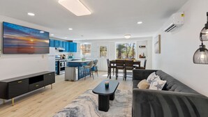 A modern living space with a kitchen, dining area, and a large TV.