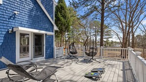 A deck with outdoor seating, a white fence, and trees in the background. - Cozy Riverfront Stay in Wareham (Wareham)