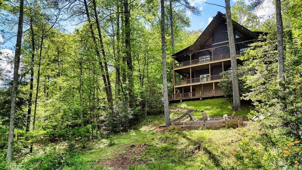 A cabin with a wooden exterior, multiple balconies, and a surrounding forested area with a pond.
