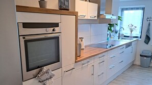 Een moderne keuken met witte kasten, een inbouwoven, een spoelbak en een raam met uitzicht.