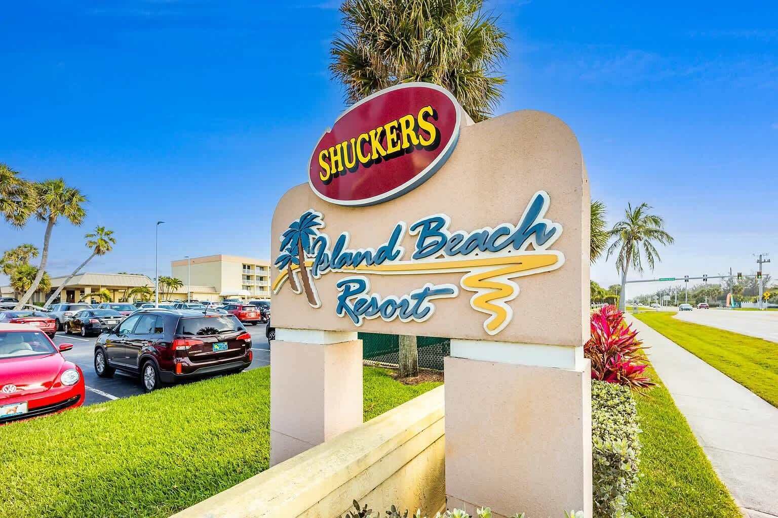 Placa indicando o Shuckers Island Beach Resort, com um estacionamento ao fundo.