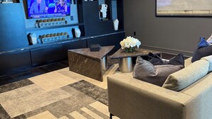 A modern living room with a large flat-screen TV, a sofa, a coffee table, and decorative items. - Houston Gem: Walk to Med Center & NRG (Houston)