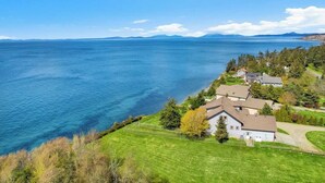 Une propriété située sur la côte, offrant une vue sur la mer, avec une pelouse et un ensemble de maisons à proximité.