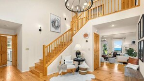 Un vaste espace de vie agrémenté d’un escalier en bois, d’un canapé blanc, d’une lampe et d’un tapis.
