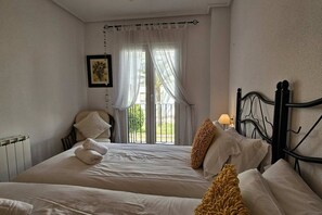 A hotel room with two beds, a radiator, a window with curtains, and a picture on the wall. - Beautiful 2 bed apartment at La Torre Golf AO711LT (Murcia)