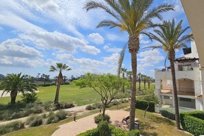 A view of a landscaped area with palm trees and a pathway leading to a building with balconies. - Beautiful 2 bed apartment at La Torre Golf AO711LT (Murcia)