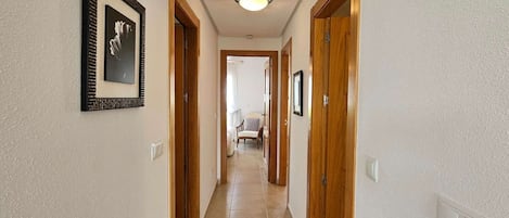 A hallway with wooden doors, a framed picture on the wall, and a ceiling light.