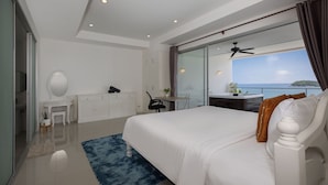 A modern bedroom with a large bed, a desk, and a view of the sea. - Ocean View Jacuzzi 3BR Kata Penthouse (Karon)