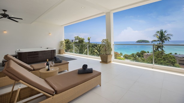 A spacious balcony with a hot tub, lounge chairs, and a view of the ocean. - Ocean View Jacuzzi 3BR Kata Penthouse (Karon)