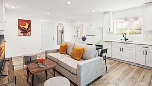 A modern living room with a sofa, coffee table, and a painting on the wall. - Modern Home Near Pasadena Garage Full Kitchen (Alhambra)
