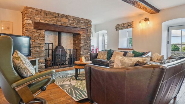 A cozy living room with a stone fireplace, leather sofa, and a television.