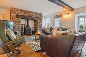 A cozy living room with a stone fireplace, leather sofa, and a television.