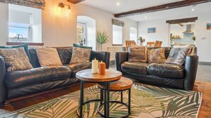 A living room with two black leather sofas, a round wooden coffee table, and a patterned rug.