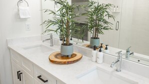 A bathroom with a white marble sink, two faucets, a mirror, and a potted plant on a wooden tray. - Near American Fork Canyon | Family & Pet Friendly (American Fork)