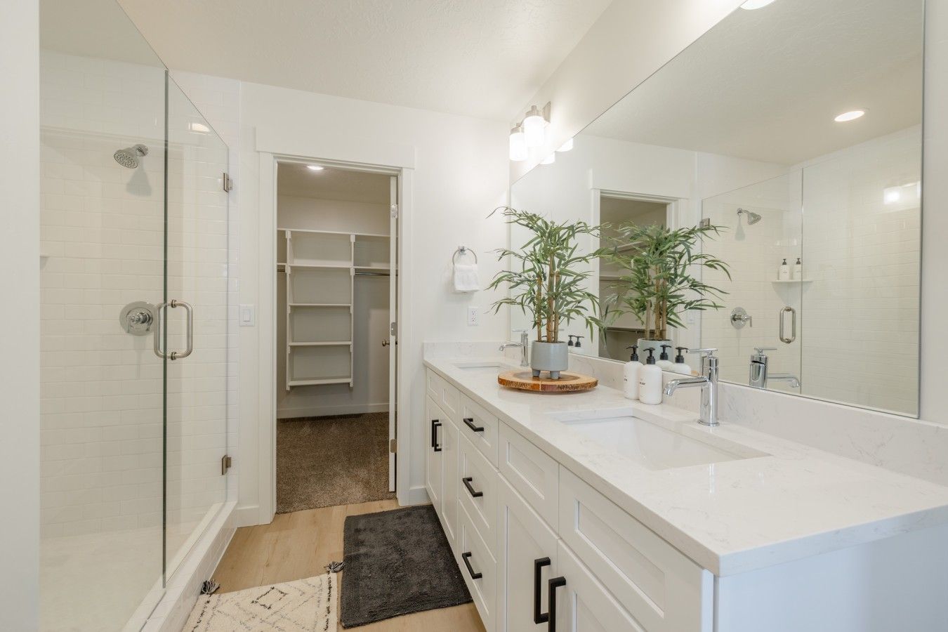A modern bathroom with a walk-in shower, a large mirror, and a vanity with a sink and storage.