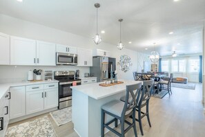 A modern kitchen with white cabinetry, stainless steel appliances, and a central island with bar stools. - Near American Fork Canyon | Family & Pet Friendly (American Fork)
